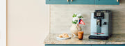 Gaggia Cadorna Prestige in Moonlight Grey on a kitchen counter top next to a pot of flowers, coffee and pastries.