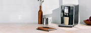 Gaggia Anima in Black on a cream and white counter top with books laying next to it in front of a white tiled wall.