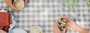 Person holding an iced coffee on a checkered table cloth.