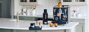 Profitec DRIVE Espresso Machine in black with wooden accents next to espresso accessories on a kitchen counter. 
