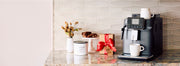 A close-up shot of the Gaggia Cadorna Style espresso machine surrounded by decorative items like a present, biscotti cookies and a Whole Latte Love Airscape coffee canister