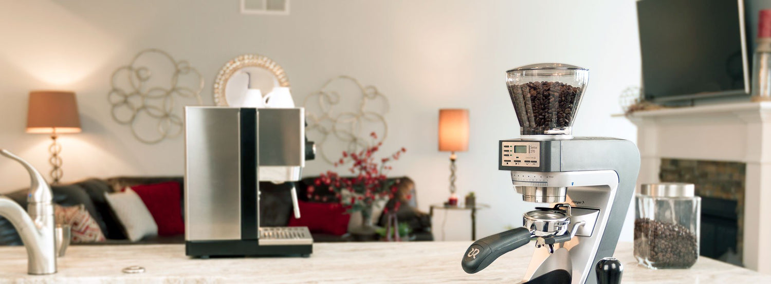 A Baratza coffee grinder in a white kitchen, next to a Gaggia Classic Pro espresso machine