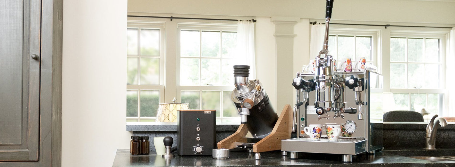 A single-dosing coffee grinder next to a lever manual espresso machine.