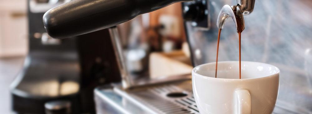 A La Marzocco espresso machine pouring brewed espresso from the spouts of a portafilter into a white coffee cup