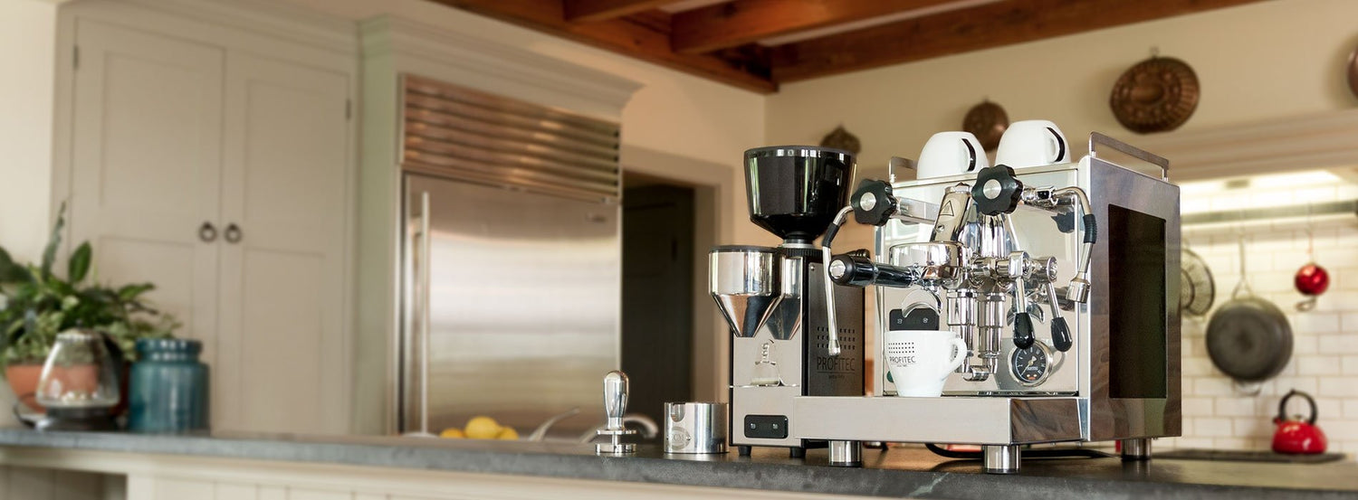 A Profitec espresso machine beside a Profitec coffee and espresso grinder, in a white kitchen.