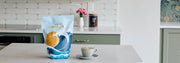 Whole Latte Love Crema Wave on a kitchen counter next to a latte with latte art.