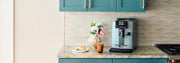 Gaggia Cadorna Prestige in Moonlight Gray on a kitchen counter next to a pastry and iced coffee drink.