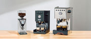 Close-up of a Gaggia MDF, Classic UP and Gaggia GT on a wooden counter top in front of a gray wall.