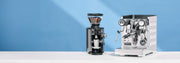 Mahlkonig X54 Coffee Grinder and Rocket Espresso Appartamento Espresso Machine on a white surface with a blue background.
