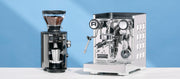 Close-up of a Mahlkonig X54 Coffee Grinder and Rocket Espresso Appartamento Espresso Machine on a white surface with a blue background.