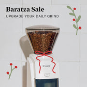 Baratza Encore coffee grinder with coffee beans on a tiled wall background