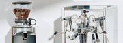 Close-up of an ECM Synchronika II with Flow Control in front of a white background next to a Ceado coffee grinder.