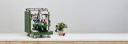 Green espresso machine on a white surface with a minimal background