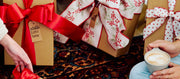Gift boxes with red ribbons and a person holding a cup of coffee.