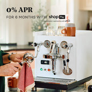 ECM Mechanika Max in white on counter with a customer cleaning a portafilter. Promotional text overlayed that reads "0% APR for 6 months with ShopPay".