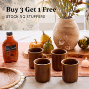 Dinner table set with 4 brown mugs a bottle of Pumpkin Pie Hollander sauce and holiday decorations with promotional text that reads Buy 3 Get 1 Free - Stocking Stuffers.