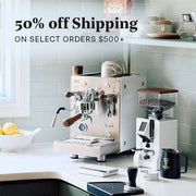 Bezzera NINI in white with wooden accents next to a Eureka Compatto Grinder in white with wood accents and other coffee accessories on a white counter top with a sage backsplash. Promotional text overlayed that reads "50% Off Shipping - On select orders $500+".