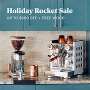 Rocket Appartamento and Rocket Grinder on a marble kitchen counter next to a stove and other espresso brewing accessories. Promotional text ovlerayed that reads "Holiday Rocket Sale - Up to $300 OFF + FREE WOOD".