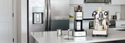 A countertop coffee setup in a modern kitchen, featuring a Lelit Steve, a Lelit Mara X and accessories on a white counter.