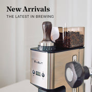 Close-up of a Lelit Steve with a Lelit tamper with a wooden handle on top. Text overlayed that reads "New Arrivals - The Latest in Brewing".