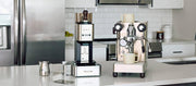 Close-up of a countertop coffee setup in a modern kitchen, featuring a Lelit Steve, a Lelit Mara X and accessories on a white counter.