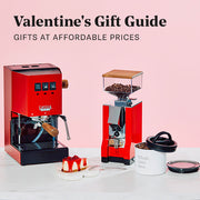 Close-up of the Cherry Red Gaggia Classic E24 next to a Red Eureka Silenzio 55 in front of a pink background and on a white counter with promotional text that reads "Valentines Day Gift Guide - Gifts at affordable prices".