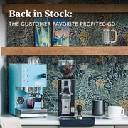 Profitec GO machine with a Eureka grinder and 2 Whole Latte Love coffees on a coffee bar with a tamping station