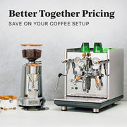 Eureka Grinder and ECM Synchronika II with wood accents on a white surface with a gray background.