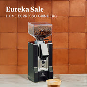Eureka Silenzio 55 in Black on a white counter in front of a orange tiled wall. Promotional text that reads "Eureka Sale - Home Espresso Grinders".