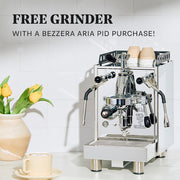 Bezzera Aria PID with Flow Control on a white counter next to a latte and flowers. Promotional text overlayed that reads "Free Grinder with a Bezzera Aria PID Purchase".