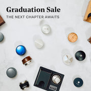 Looking down at various tampers, tamper stations and distribution tools all laid out on a white counter top. Promotional text that reads "Graduation Sale - The next chapter awaits".
