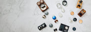 Looking down at various tampers, tamper stations and distribution tools all laid out on a white counter top. 