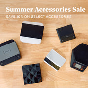 Looking down at various varia, brewista and acaia scales laid out on a wooden counter top. Promotional text overlayed that reads "Summer Accessories Sale - Save 10% on select accessories".
