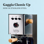 Gaggia Classic UP in Stainless Steel with Tiger Maple accents on a blue background. Promotional text overlayed that reads "Gaggia Classic UP - Now in Stainless Steel".