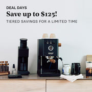 The Gaggia UP setup with coffee beans, and coffee cups on a counter and a Varia VS4 Grinder. Promotional text overlayed that reads "Deal Days - Save up to $125! Tiered Savings for a limited time".