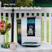 Silver JURA Z6 Super-Automatic espresso machine on an outside table next to grapes, coffee cup and flowers. Promotional text overlayed that reads "Deal Days: Summer Refurb Sale - Certified Refurbished Products".