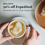 Person holding a cup of coffee with latte art. Promotional text overlayed that reads "Deal Days: 50% Off Expedited Shipping with your purchase".