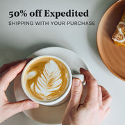 Person holding a cup of coffee with latte art, promotional text for expedited shipping.