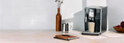 Gaggia Anima in Black on a cream and white counter top with books laying next to it in front of a white tiled wall.