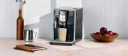 Close-up of the Gaggia Anima in Black on a cream and white counter top with books laying next to it in front of a white tiled wall.