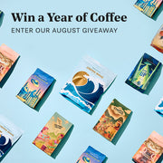 Promotional graphic for a coffee giveaway with the text 'Win a Year of Coffee' and 'ENTER OUR AUGUST GIVEAWAY' on a light blue background, surrounded by several Whole Latte Love coffee bags.