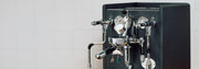 Espresso machine with a flow control device on a white tiled wall background