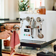 ECM Mechanika Max in white on a counter with a person cleaning a portafilter.