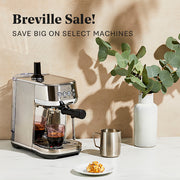 Breville Bambino espresso machine on a table with a vase of eucalyptus and a plate of food, with 'Breville Sale!' text above.