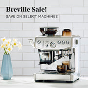 Breville Barista Express Impress on a white counter in front of a white tiled wall. Promotional text overlayed that reads "Breville Sale! Save on Select Machines".