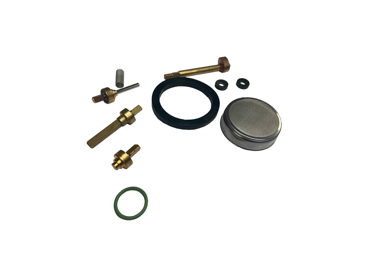 A set of small mechanical parts and seals laid out on a plain white background, including brass-toned metal components, a black rubber ring, a silver circular metal piece, a green O-ring, and small black washers.