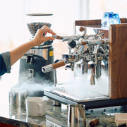 Person making coffee using an espresso machine on a marble counter.