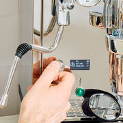 Hand adjusting a PID knob on an espresso machine.
