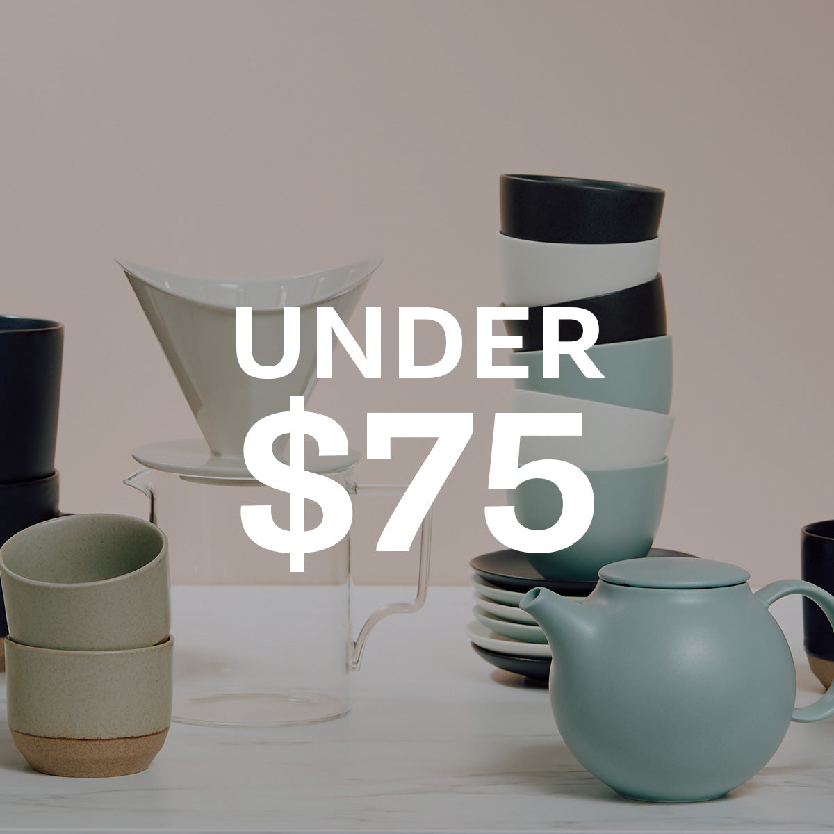 A collection of matte ceramic tableware including a light blue-green teapot, stacked bowls in black, white, and pale blue-green, a beige cup, and a white filter, displayed on a white surface against a beige background with a large white text overlay reading 'UNDER $75'.