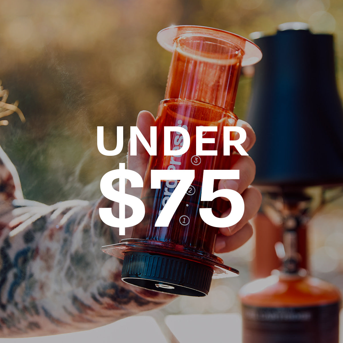Close-up of a Person holding a AeroPress Coffee Maker in Red. Text overlayed that says UNDER $75.